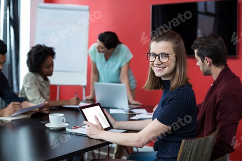 Preview: Portrait Of Business Executive Using Digital Tablet And Colleague Working In Background In Office
