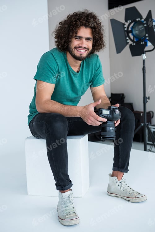 Preview: Portrait Of Happy Photographer Holding A Camera In The Studio