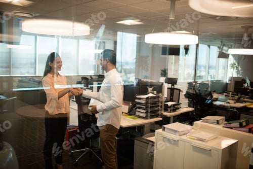 Preview: Business Colleagues Shaking Hands In Office Seen Through Glass