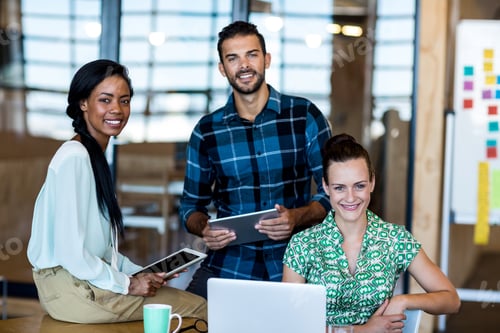 Preview: Portrait Of Young Man And Women Sitting At Their Desk And Using Laptop In The Office