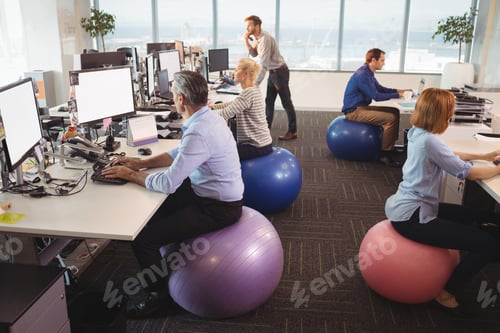 Preview: Business People Sitting On Exercise Balls While Working At Desk In Office