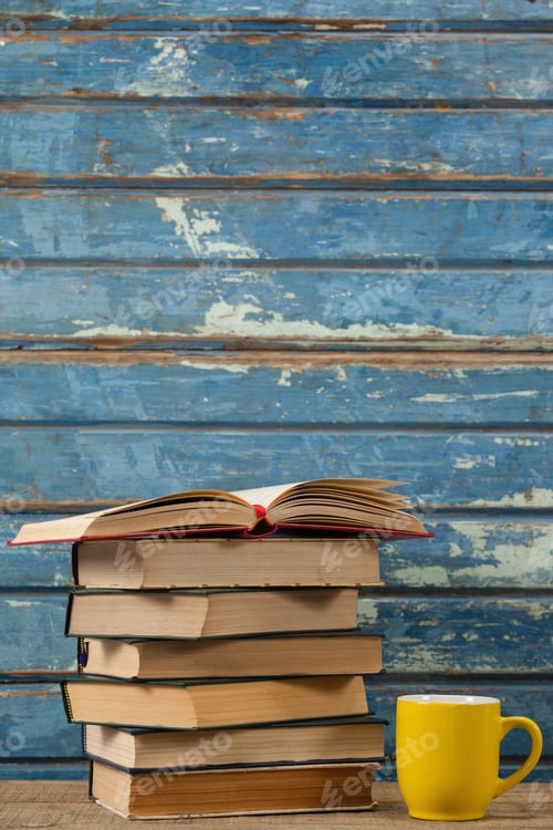 Preview: Stack Of Books And Coffee Cup Against Blue Wooden Background