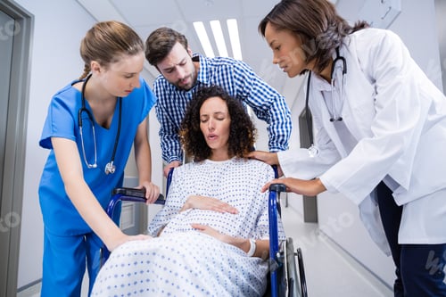 Preview: Doctors And Man Comforting Pregnant Woman In Corridor Of Hospital
