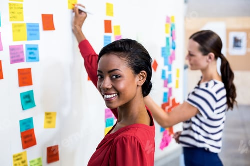 Preview: Young Woman Smiling At Camera While Writing On White Board In The Background