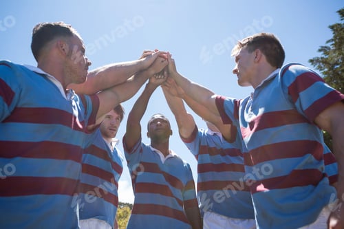 Preview: Low Angle View Of Rugby Team With Arms Raised Standing Against Sky