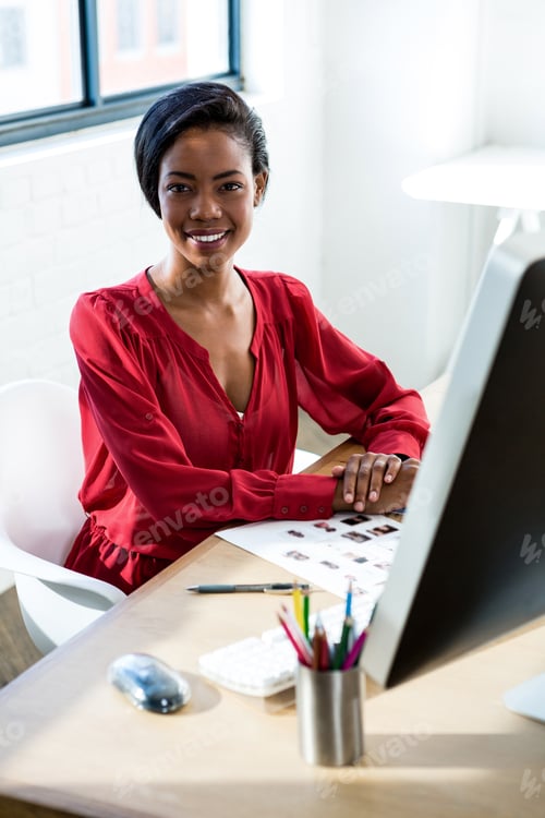 Preview: Portrait Of Woman Sitting At Desk And Smiling In Office