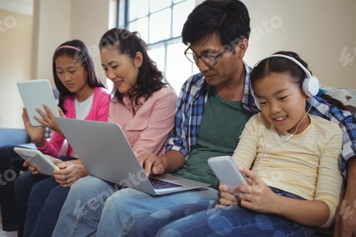 Preview: Family Using Laptop, Digital Tablet And Mobile Phone In Living Room At Home