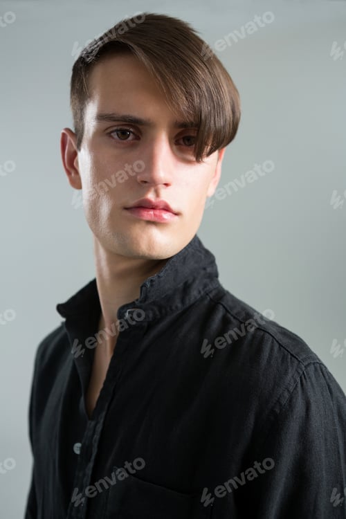 Preview: Androgynous Man Looking At Camera Against Grey Background