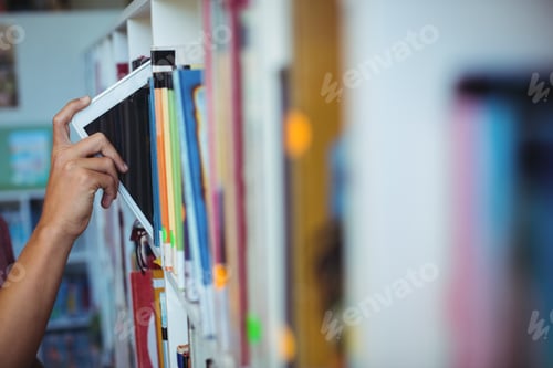 Preview: Hand Of Student Keeping Digital Tablet In Bookshelf In Library At School