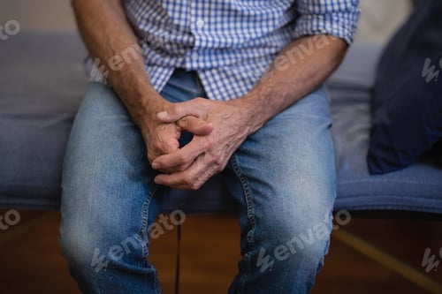 Preview: Midsection Of Senior Male Patient Sitting With Hands Clasped On Bed At Hospital Ward