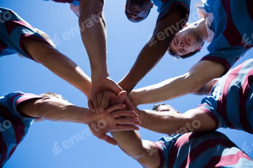 Preview: Low Angle View Of Rugby Team Holding Hands While Standing Against Clear Sky