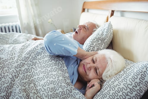Preview: Man Snoring And Woman Covering Her Ears While Sleeping On Bed In Bedroom