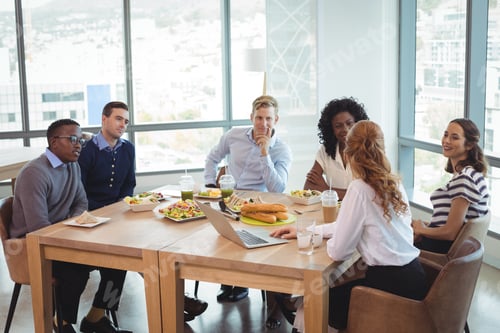 Preview: Business People Discussing While Sitting Around Breakfast Table At Office Cafeteria