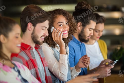 Preview: Woman Talking On Smartphone While Friends Using Mobile Phone In Pub