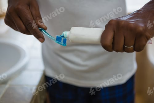 Preview: Mid Section Of Man Applying Toothpaste On Brush In Bathroom At Home