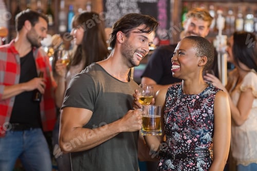 Preview: Happy Young Couple Holding Beer Mugs In Bar