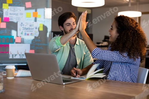 Preview: Creative Business People Giving High Five To Each Other At Desk In Office