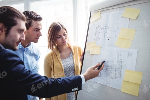 Preview: Businessman Explaining Blueprints To Coworkers In Creative Office