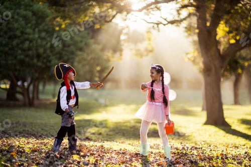 Preview: Full Length Of Playful Siblings Wearing Costumes At Park On Sunny Day