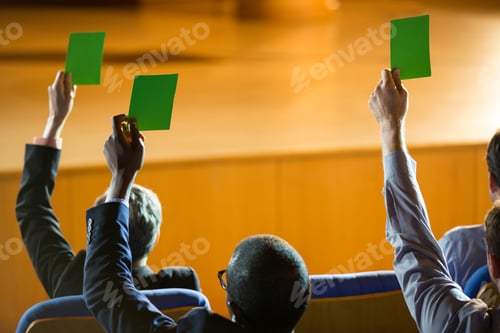 Preview: Rear View Of Business Executives Show Their Approval By Raising Hands At Conference Center