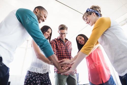 Preview: Low Angle View Of Business People Stacking Hands While Standing In Office