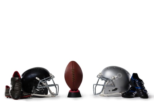 Preview: American Football On Tee By Sports Shoes And Helmets Against White Background