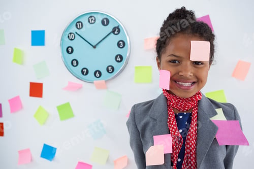 Preview: Happy Businesswoman With Adhesive Notes Stuck On Suit And Head Standing Against Wall