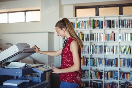 Preview: Happy Schoolgirl Using Xerox Photocopier In Library At School