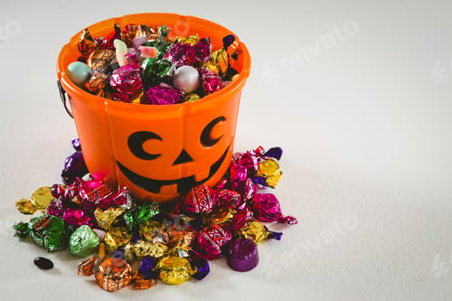 Preview: High Angle View Of Bucket With Various Sweet Food Over White Background During Halloween