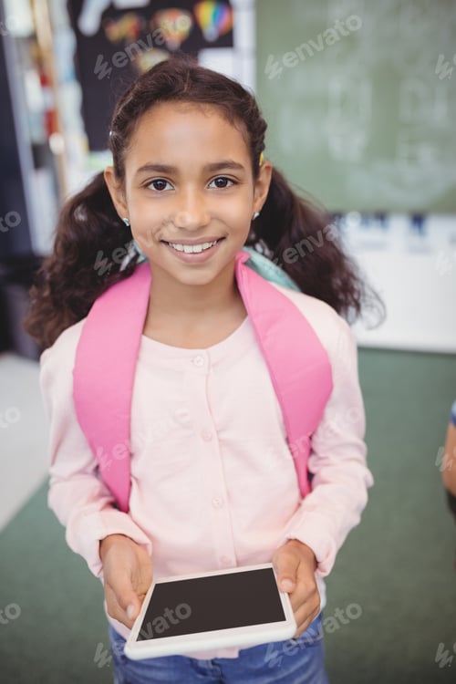 Retrato de uma linda garota em pé com tablet digital na escola
