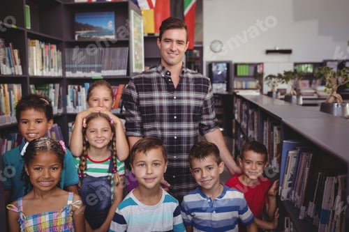 Preview: Portrait Of Happy Teacher And Schoolkids Standing Together In Library At School
