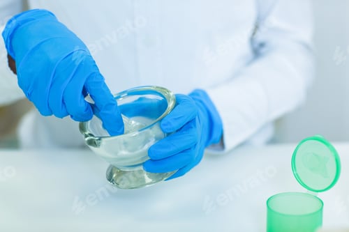 Preview: Mid-Section Of Pharmacist Grinding Medicine In Mortal And Pestle At Pharmacy