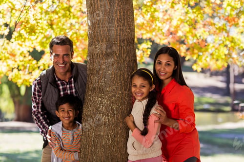 Vista previa: Portrait Of Smiling Family Standing By Tree At Park