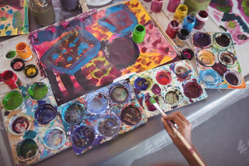 Preview: Cropped Hand Of Child Holding Brush By Color Palettes On Desk