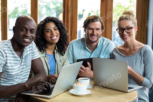 Preview: Portrait Of Friends Using Laptop And Digital Tablet While Having Coffee In Cafe