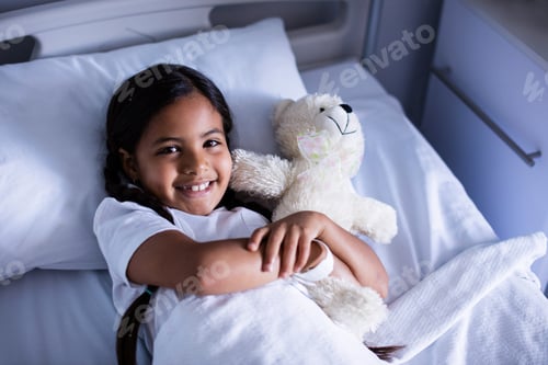 Preview: Portrait Of Smiling Patient Relaxing On Bed With Teddy Bear In Hospital