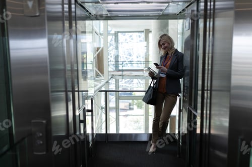 Preview: Front View Of Happy Young Blonde Caucasian Businesswoman Using Mobile Phone In Modern Office