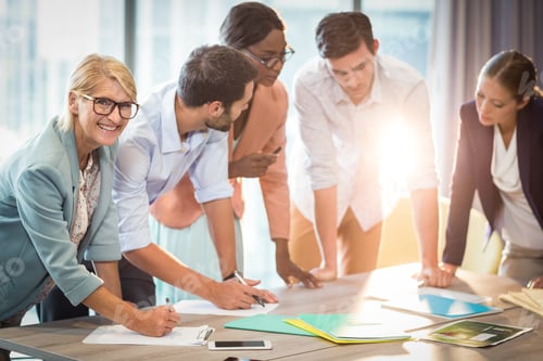 Preview: Group Of Business People Discussing At Desk In The Office