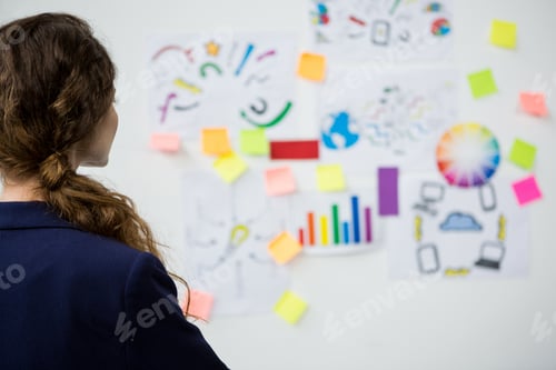 Preview: Woman Looking At Adhesive Notes On Wall In Creative Office