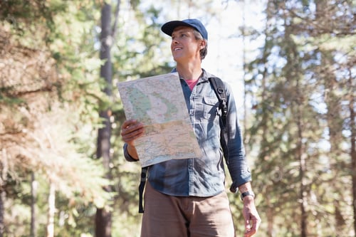 Preview: Low Angle View Of Mature Male Hiker With Map Standing In Forest