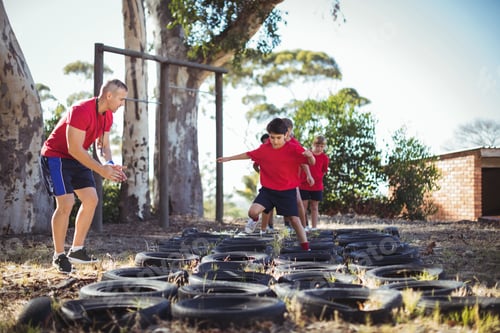 Preview: Trainer Instructing Kids During Tyres Obstacle Course Training In The Boot Camp