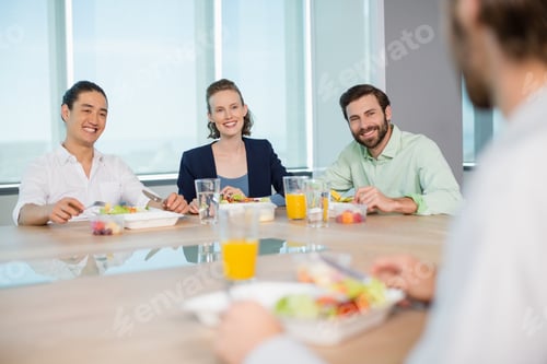 Preview: Smiling Business Executives Interacting While Having Meal In Office