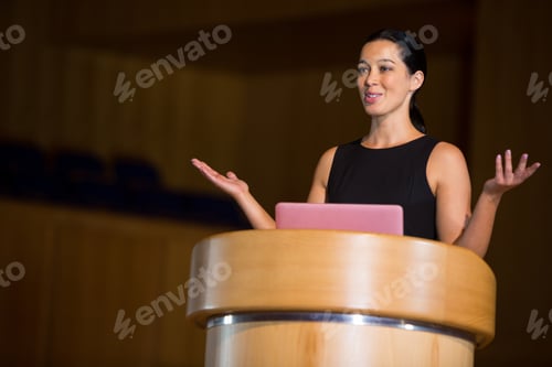 Preview: Female Business Executive Giving A Speech At Conference Center