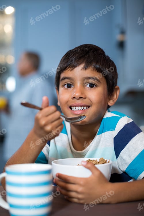 Visualização: Retrato de perto de menino tomando café da manhã com cereais em casa