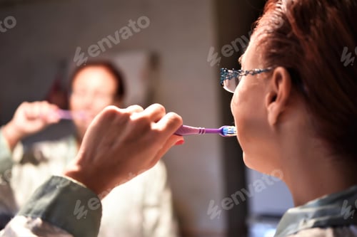 Preview: Beautiful Woman Brushing Teeth After Eating In Front Of A Mirror In The Bathroom.