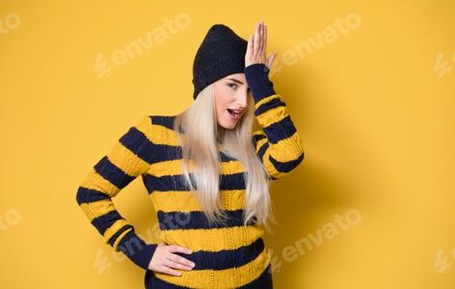 Preview: Forget Concept. Cute Girl Touching Her Forehead, Model Wearing Woolen Cap And Sweater, Isolated On