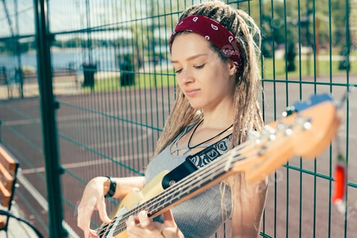 Preview: Calm Young Musician Thoughtfully Playing The Guitar While Leaning On The Chain Link Fence