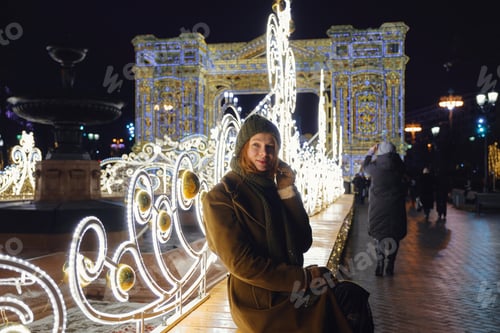 Preview: Young Smiling Woman Posing On The Street. Festive Christmas Fair In The Background. Model Wearing A