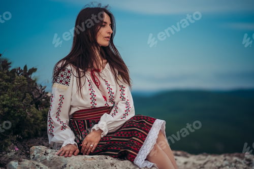 Preview: Attractive Woman In Traditional Romanian Costume On Mountain Green Blurred Background. Outdoor