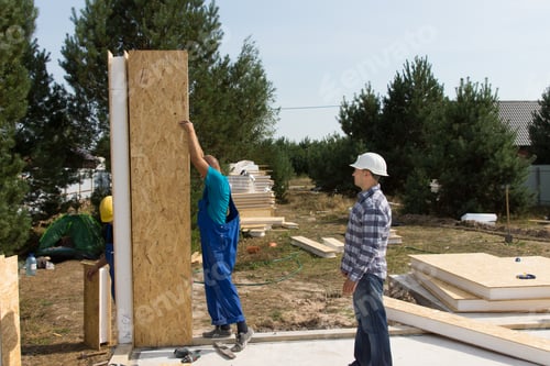 Preview: Group Of Builders Erecting Insulated Wooden Wall Panels On The Newly Laid Floor Of A New Build
